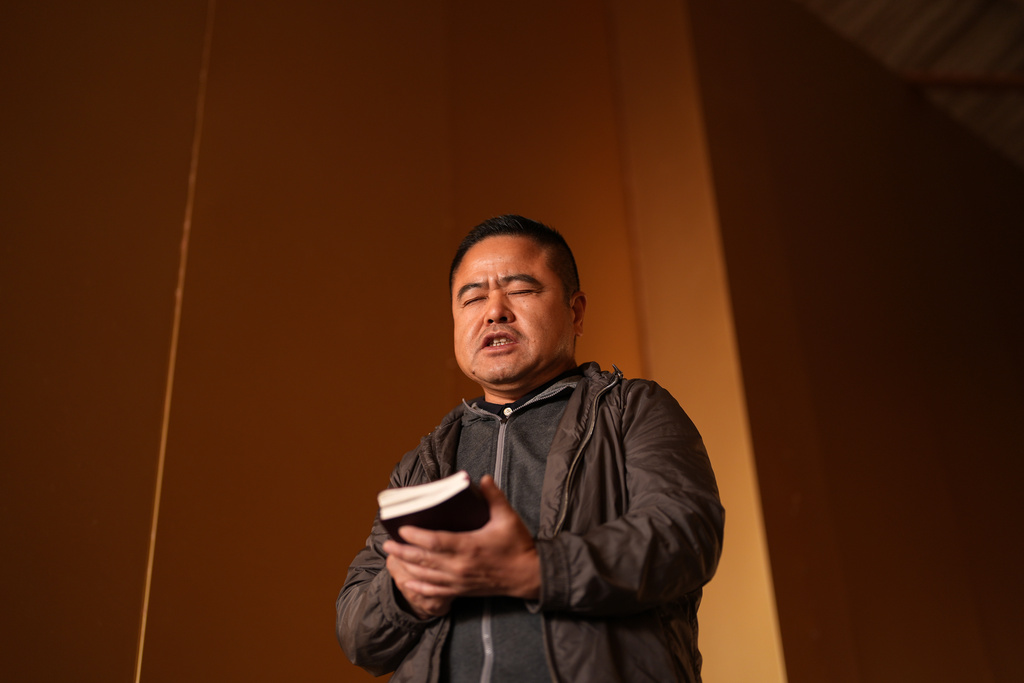Former Chinese official Li Chuanliang holds a Bible as he prays inside the Mayflower Church temple sanctuary in Midland, Texas, Jan. 18, 2025. (AP Photo/Rebecca Blackwell)