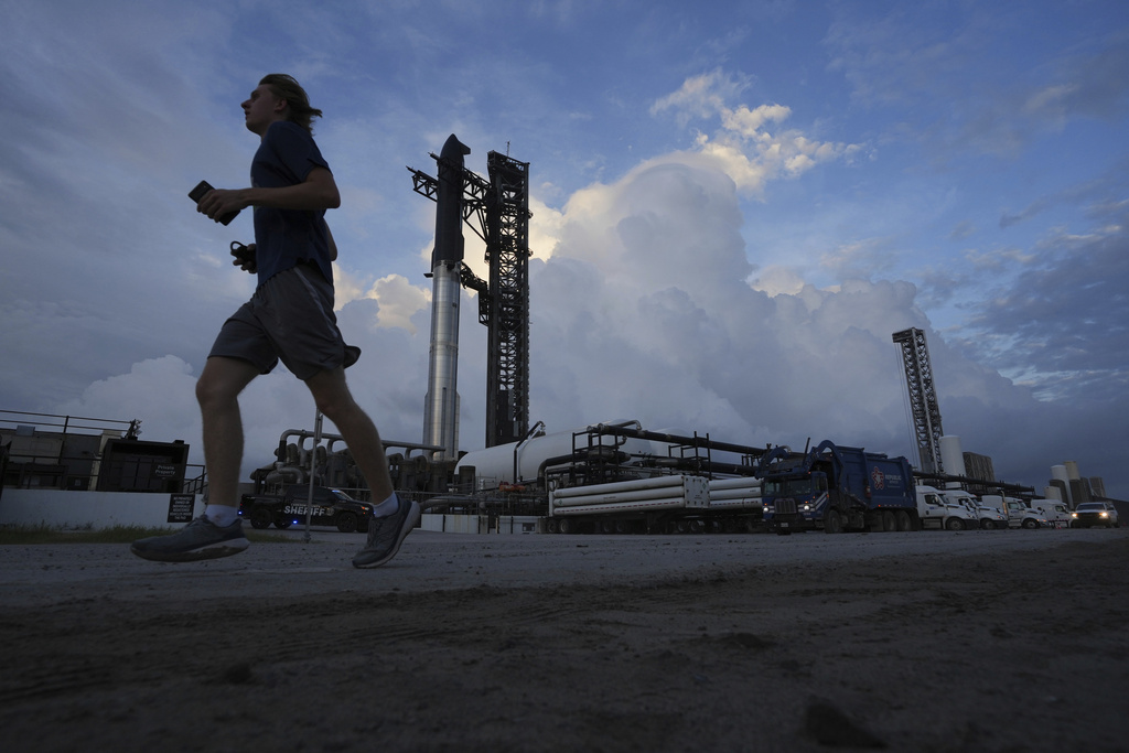 A jogger passes as SpaceX's mega rocket Starship is prepared for a test flight from Starbase, Texas, Tuesday, Aug. 26, 2025. (AP Photo/Eric Gay)