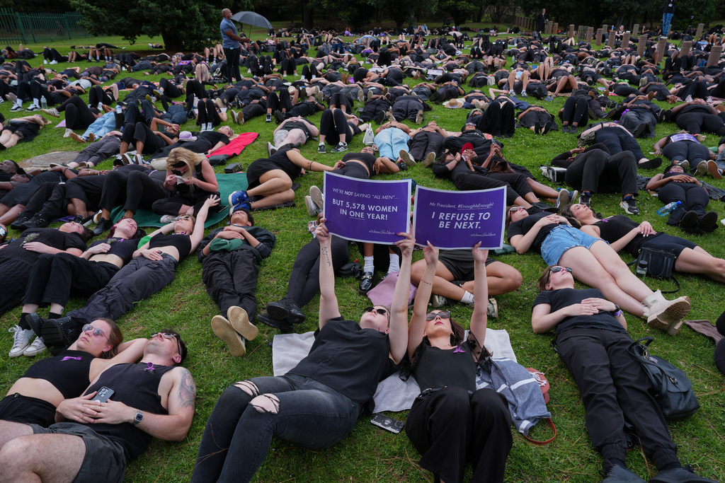 Participants hold signs while lying on the ground during a gender-based violence protest at the forecourt of the botanical gardens in Johannesburg, South Africa, Friday, Nov. 21, 2025. (Misper Apawu)