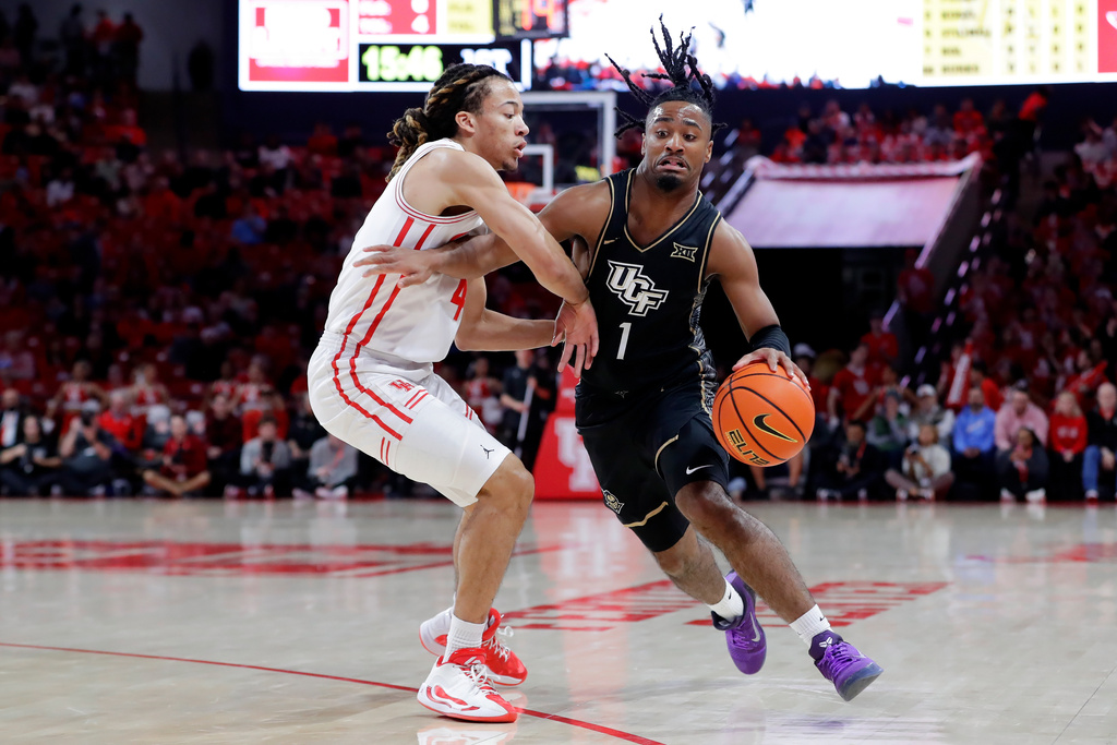 Central Florida guard Themus Fulks (1) drives around Houston guard Kingston Flemings, left, during the first half of an NCAA college basketball game, Wednesday, Jan., 4, 2026, in Houston. (AP Photo/Michael Wyke)