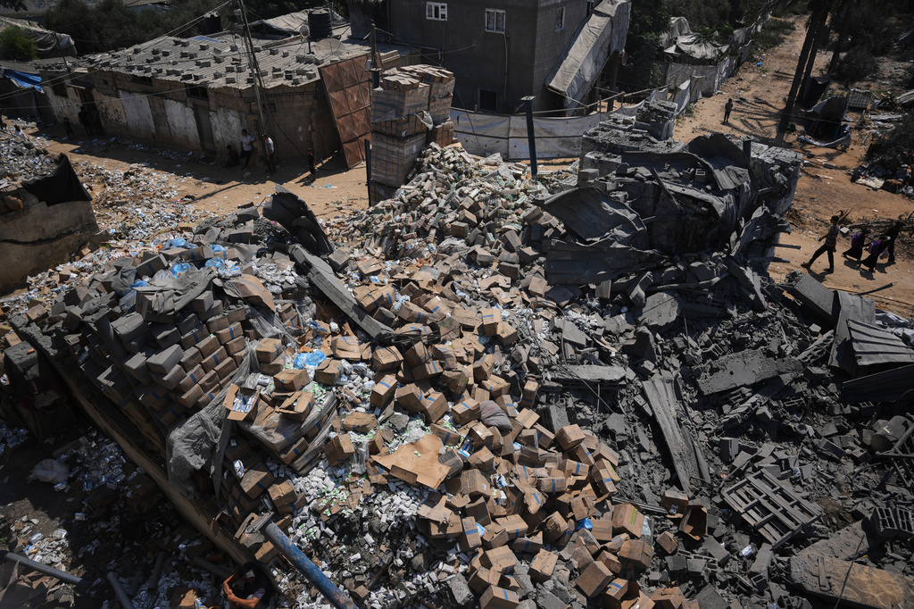 Palestinians walk past a food-aid warehouse damaged in an Israeli airstrike that targeted a nearby house in Deir al-Balah, central Gaza Strip, Wednesday, Aug. 26, 2026. (AP Photo/Abdel Kareem Hana)