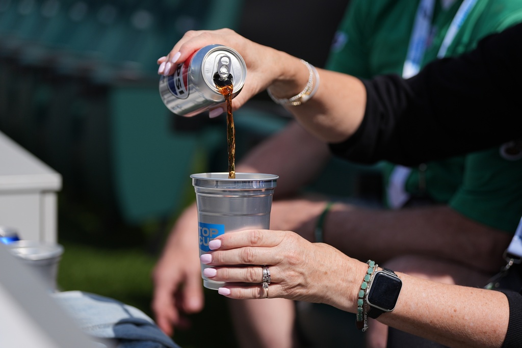 A fan pours a drink into an aluminum cup during an NFL football game in Philadelphia, Sunday, Sept. 21, 2025. (AP Photo/Matt Rourke)