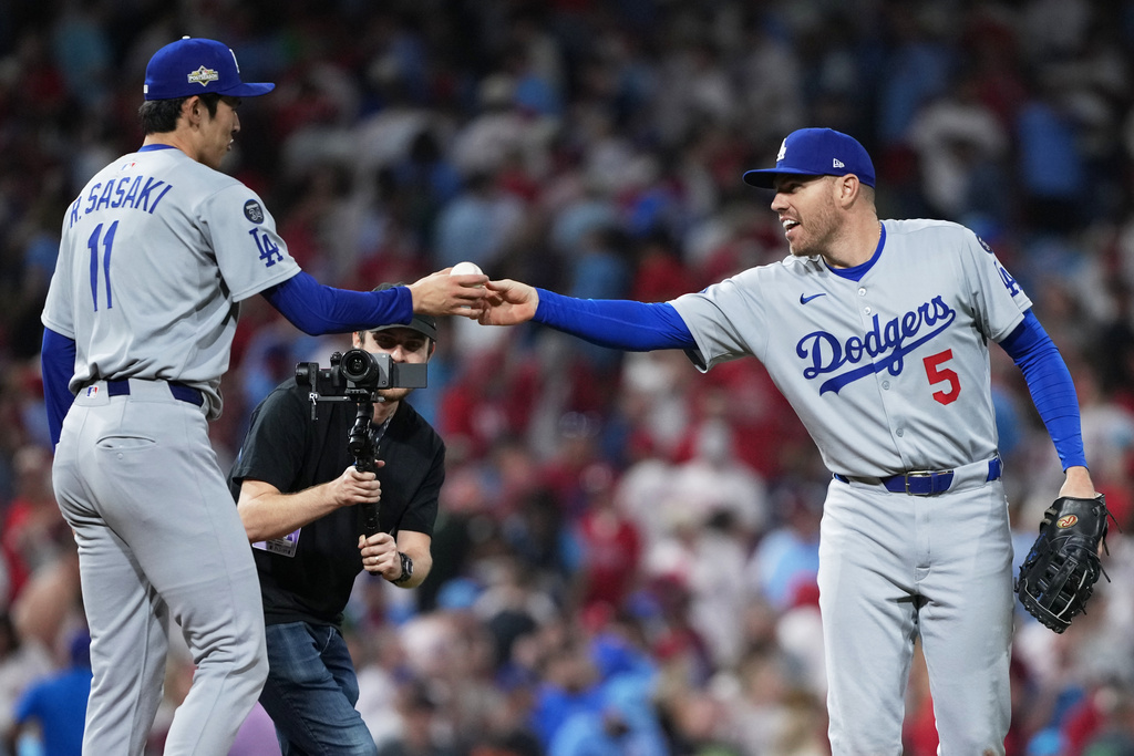 Los Angeles Dodgers first baseman Freddie Freeman, right, hands a ball to relief pitcher Roki Sasaki after the team's win in Game 2 of baseball's National League Division Series against the Philadelphia Phillies, Monday, Oct. 6, 2025, in Philadelphia. (AP Photo/Matt Slocum)