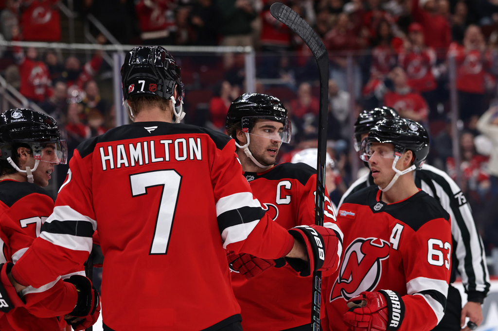 New Jersey Devils center Nico Hischier (13) is congratulated by Jesper Bratt (63) and Dougie Hamilton (7) after scoring a goal during the second period of an NHL hockey game against the Vancouver Canucks, Saturday, Oct. 10, 2026, in Newark, N.J. (AP Photo/Adam Hunger)