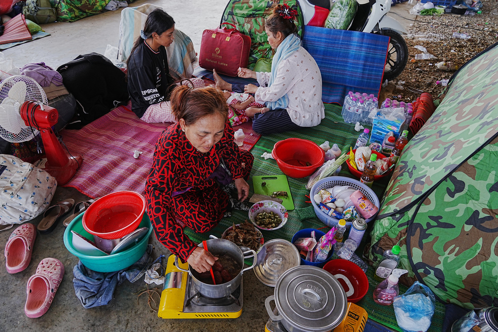 Evacuees cook food as they take refuge in Banteay Menchey provincial town, Cambodia, Saturday, Dec. 13, 2025, after fleeing homes following fighting between Thailand and Cambodia. (AP Photo/Heng Sinith)
