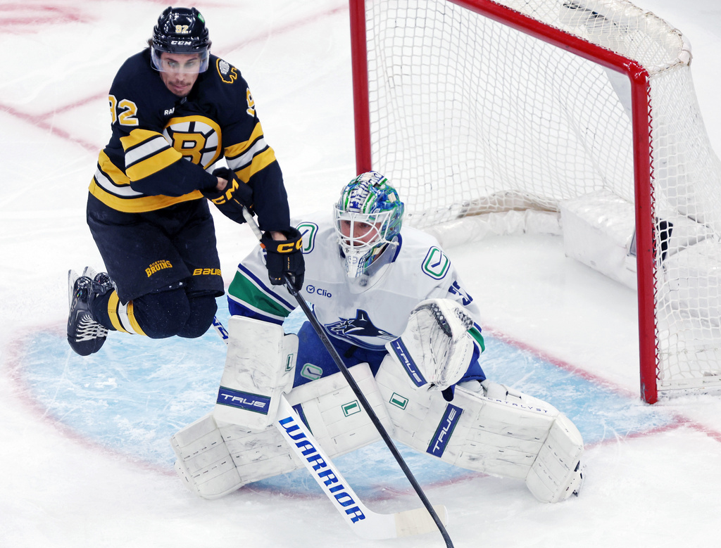 Boston Bruins forward Marat Khusnutdinov, left, leaps in front of Vancouver Canucks goalie Kevin Lankinen, right, in the first period of an NHL hockey game, Saturday, Dec. 20, 2025, in Boston. (AP Photo/Jim Davis)