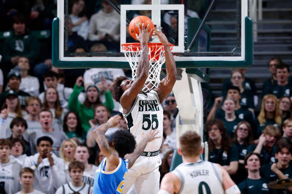 Michigan State forward Coen Carr (55) attempts a reverse dunk against UCLA guard Donovan Dent, left, during the first half of an NCAA college basketball game, Tuesday, Feb. 17, 2026, in East Lansing, Mich. (AP Photo/Al Goldis)