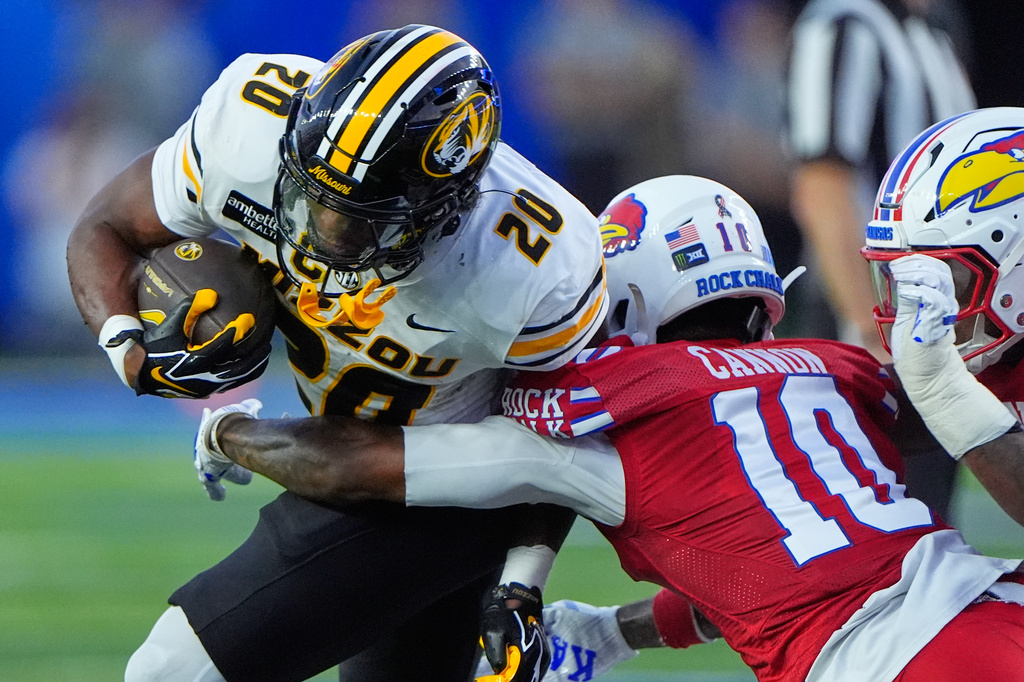 Missouri running back Jamal Roberts (20) is tackled by Kansas cornerback Elijah Cannon (10) during the first half of an NCAA college football game Friday, Sept. 11, 2026, in Lawrence, Kan. (AP Photo/Charlie Riedel)