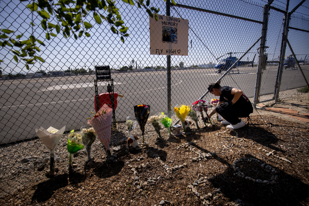A person adjusts flowers at a memorial for Eliana Moreno and George Marciniw, who died in a helicopter crash the day prior while covering an accident for a television station, at the site where their helicopter used to park at Whiteman Airport in Los Angeles, Wednesday, Sept. 16, 2026. (AP Photo/Ethan Swope) ADDITION: Adds in a helicopter crash the day prior while covering an accident for a television station.