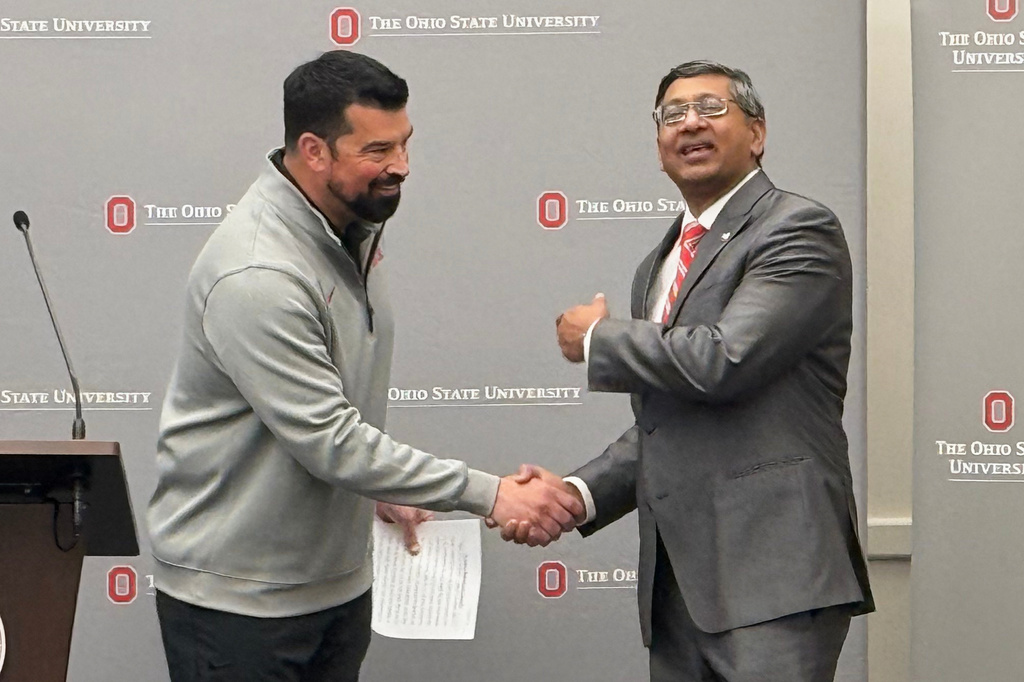 The Ohio State University head football coach Ryan Day, left, shakes hands with the university's new president, Ravi Bellamkonda, at Ohio State University on Thursday, March 12, 2026, in Columbus, Ohio. (AP Photo/Patrick Aftoora-Orsagos)
