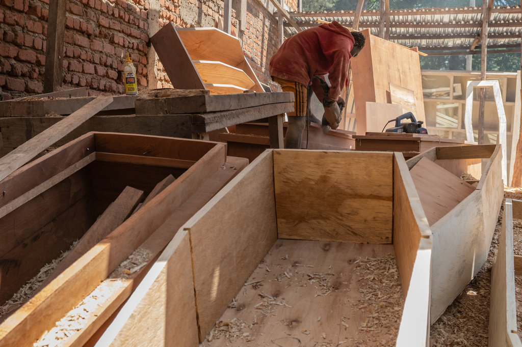 David Zaki, 19, makes a coffin at a carpentry shop in Bunia, Congo, Friday, May 22, 2026. (AP Photo/Moses Sawasawa)