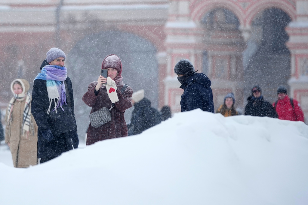 People stop to take photos at Red Square during heavy snowfall in Moscow, Russia, Friday, Jan. 9, 2026. (AP Photo/Pavel Bednyakov)