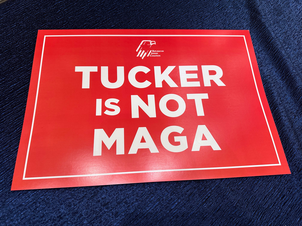 A red sign stating "Tucker is not MAGA," waved by college students attending the Republican Jewish Coalition conference in protest of the conservative talk show host's interview of right-wing podcaster Nick Fuentes, who has espoused antisemitic beliefs, is pictured at the Venetian Resort, Saturday, Nov. 1, 2025, in Las Vegas. (AP Photo/Thomas Beaumont)