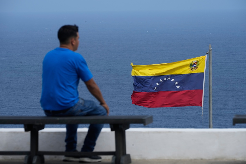 A man looks out at the sea in the city of La Guaira, Venezuela, where the nation's flag flies, Wednesday, Dec. 17, 2025. (AP Photo/Ariana Cubillos)