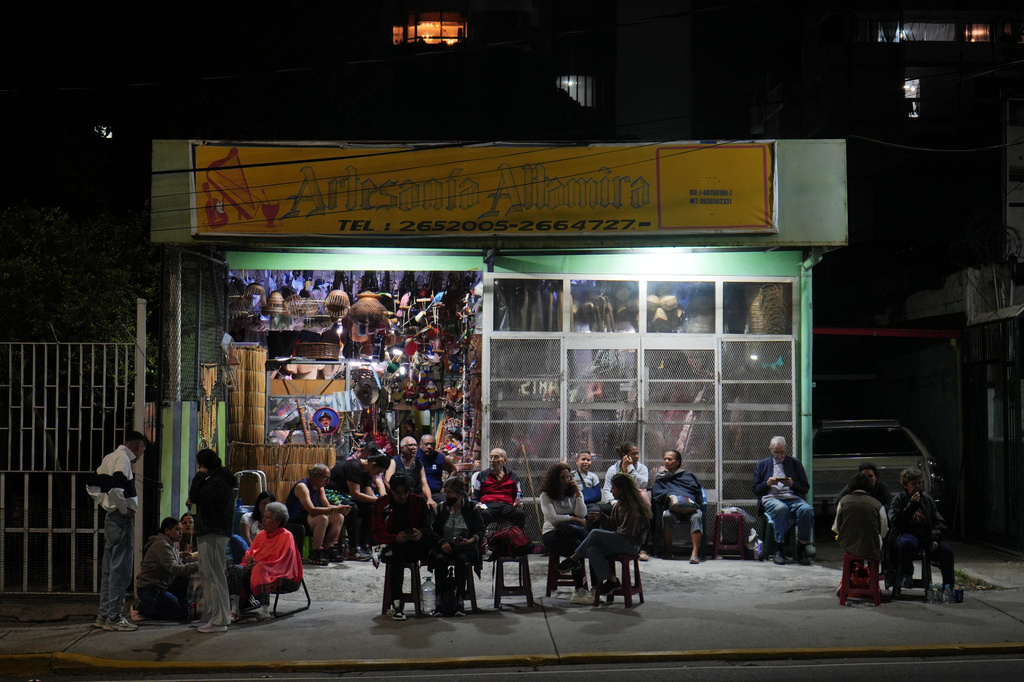 Neighbors gather outside a shop that has power after an earthquake in Caracas, Venezuela, Wednesday, June 24, 2026. (AP Photo/Adrian Naranjo)