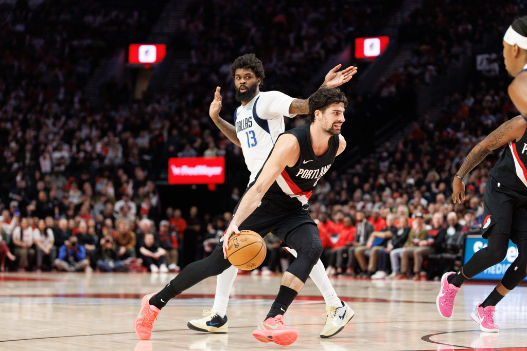 Portland Trail Blazers forward Deni Avdija, middle, drives to the basket against Dallas Mavericks forward Naji Marshall, left, during the second half of an NBA basketball game Monday Dec. 29, 2025, in Portland, Ore. (AP Photo/Howard Lao)