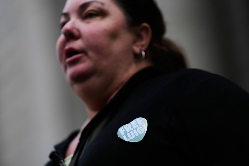 A woman wearing a "Free Luigi" pin talks to reporters outside a federal courthouse in New York, Monday, June 29, 2026. (AP Photo/Seth Wenig)