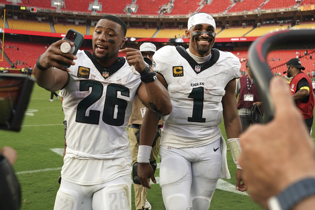 Philadelphia Eagles quarterback Jalen Hurts (1) and running back Saquon Barkley celebrate as they walk off the field following a victory over the Kansas City Chiefs in an NFL football game Sunday, Sept. 14, 2025, in Kansas City, Mo. (AP Photo/Ed Zurga)