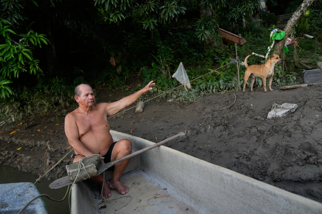 Fisherman Alvaro Molina, who lives along the banks of the Magdalena River and says he regularly encounters hippos descended from animals once kept by drug trafficker Pablo Escobar, sits in his boat in Puerto Triunfo, Colombia, Thursday, April 23, 2026. (AP Photo/Fernando Vergara)