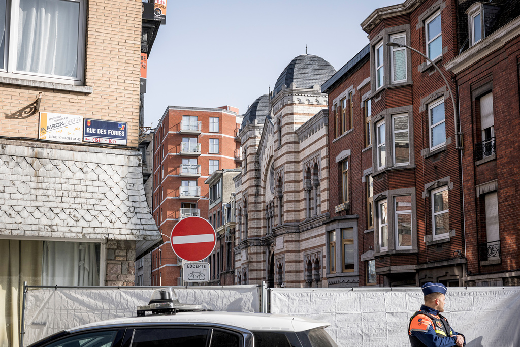 Police stand near a fence as they secure an area after a blast near a synagogue in Liege, Belgium, Monday, March 9, 2026. (AP Photo/Valentin Bianchi)