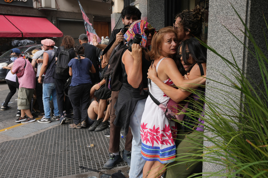 People take cover as police and protesters clash during a march by trade unions and opposition groups against a labor reform bill proposed by President Javier Milei's government in Buenos Aires, Argentina, Wednesday, Feb. 11, 2026. (AP Photo/Rodrigo Abd)