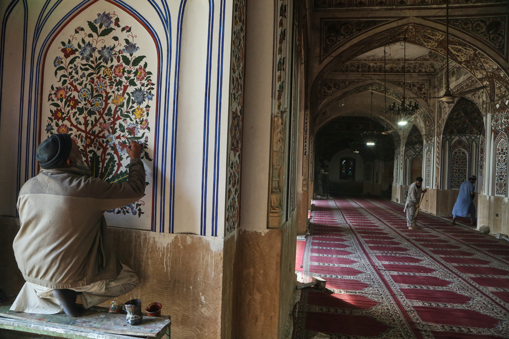 A painter gives finish touches to an artwork as workers clean an area of the historic Mahabat Khan mosque in preparation for the upcoming Muslim fasting month of Ramadan, in Peshawar, Pakistan, Monday, Feb. 16, 2026. (AP Photo/Muhammad Sajjad)