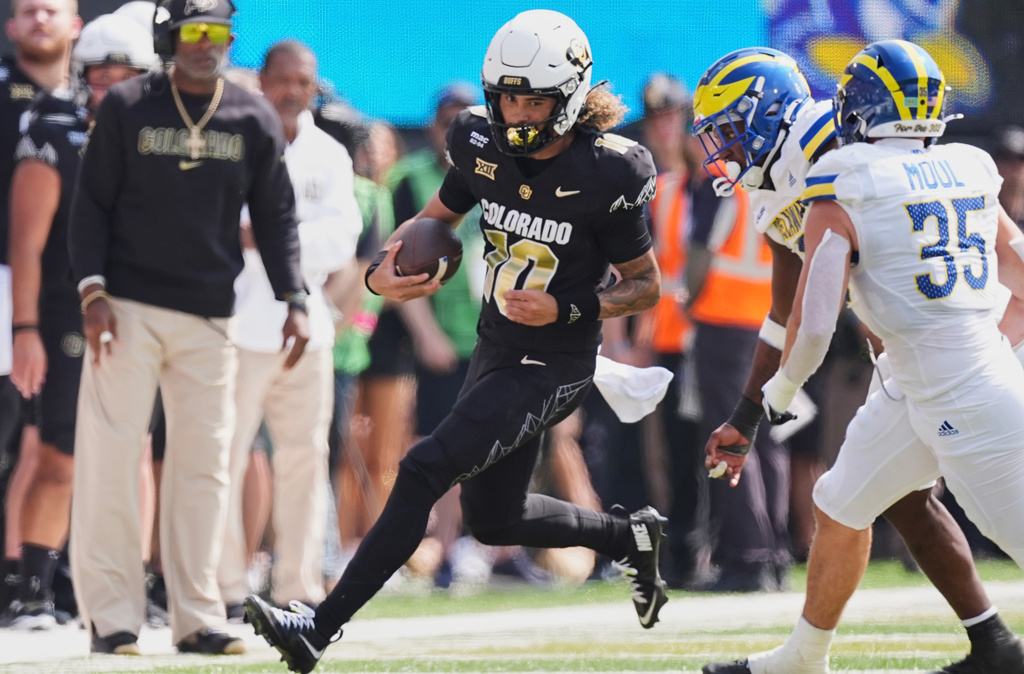 Colorado quarterback Julian Lewis, left, runs for a short gain as Delaware defensive end Q'yaeir Price, back right, and linebacker Gavin Moul pursue in the first half of an NCAA college football game Saturday, Sept. 6, 2025, in Boulder, Colo. (AP Photo/David Zalubowski)