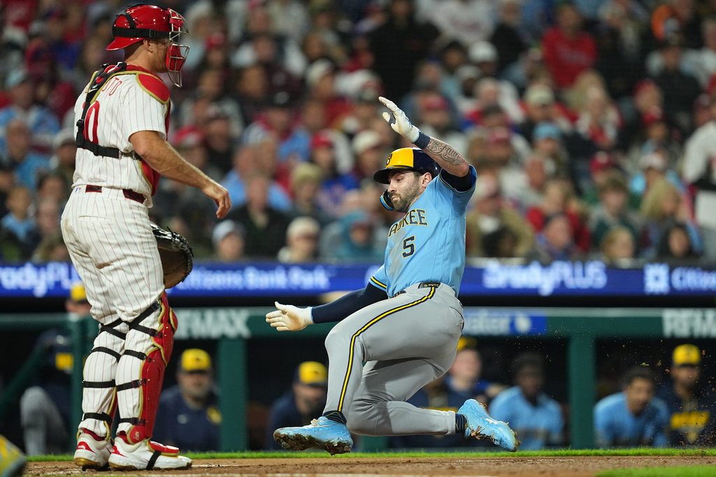 Milwaukee Brewers' Garrett Mitchell (5) scores past Philadelphia Phillies catcher J.T. Realmuto during the fourth inning of a baseball game, Tuesday, Sept. 22, 2026, in Philadelphia. (AP Photo/Matt Rourke)
