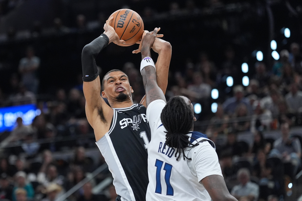San Antonio Spurs forward Victor Wembanyama (1) grabs a rebound over Minnesota Timberwolves center Naz Reid (11) during the first half of Game 5 of an NBA basketball second-round playoffs series in Minneapolis, Tuesday, May 12, 2026. (AP Photo/Eric Gay)