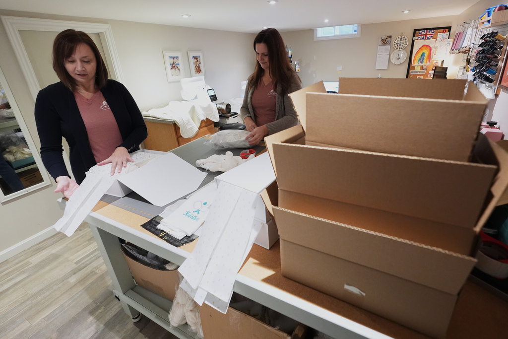 Fran Poirier, left, and her sister, Sue Bacarro, right, fill orders at their Etsy shop, Digi Wildflowers, Thursday, Oct. 30, 2025, in Windsor, Ontario, Canada. (AP Photo/Paul Sancya)