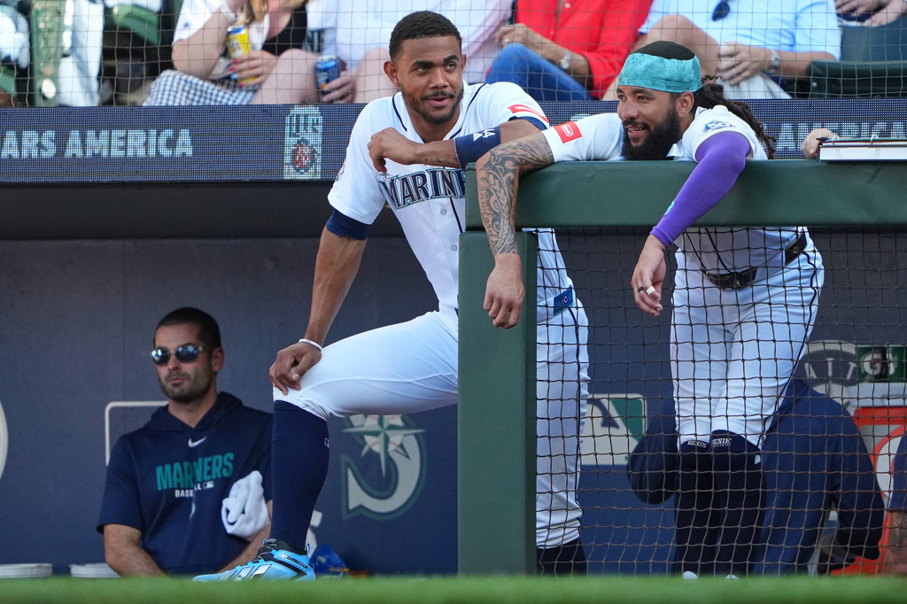 Seattle Mariners designated hitter Julio Rodríguez and J.P. Crawford talk at the dugout railing during the second inning of a baseball game against the San Francisco Giants, Saturday, July 18, 2026, in Seattle. (AP Photo/Lindsey Wasson)