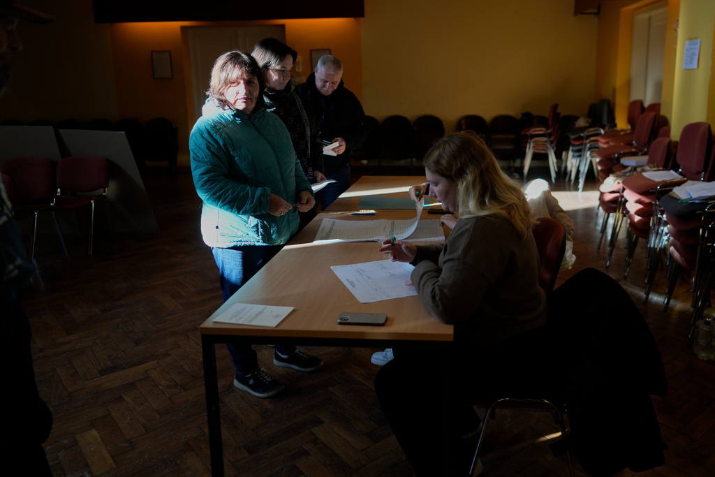 Voters register at a polling station during the referendum on assisted dying for terminally ill patients, in Domzale, Slovenia, Sunday, Nov. 23, 2025. (AP Photo/Darko Bandic)
