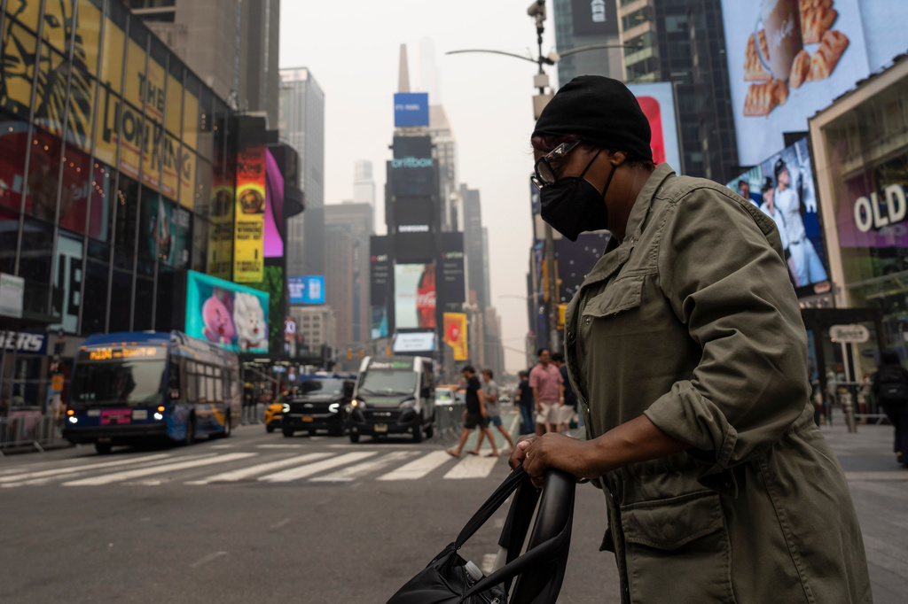 A person wearing a mask walks in Times Square as smoke from wildfires blankets the sky, Thursday, July 16, 2026, in New York. (AP Photo/Yuki Iwamura)
