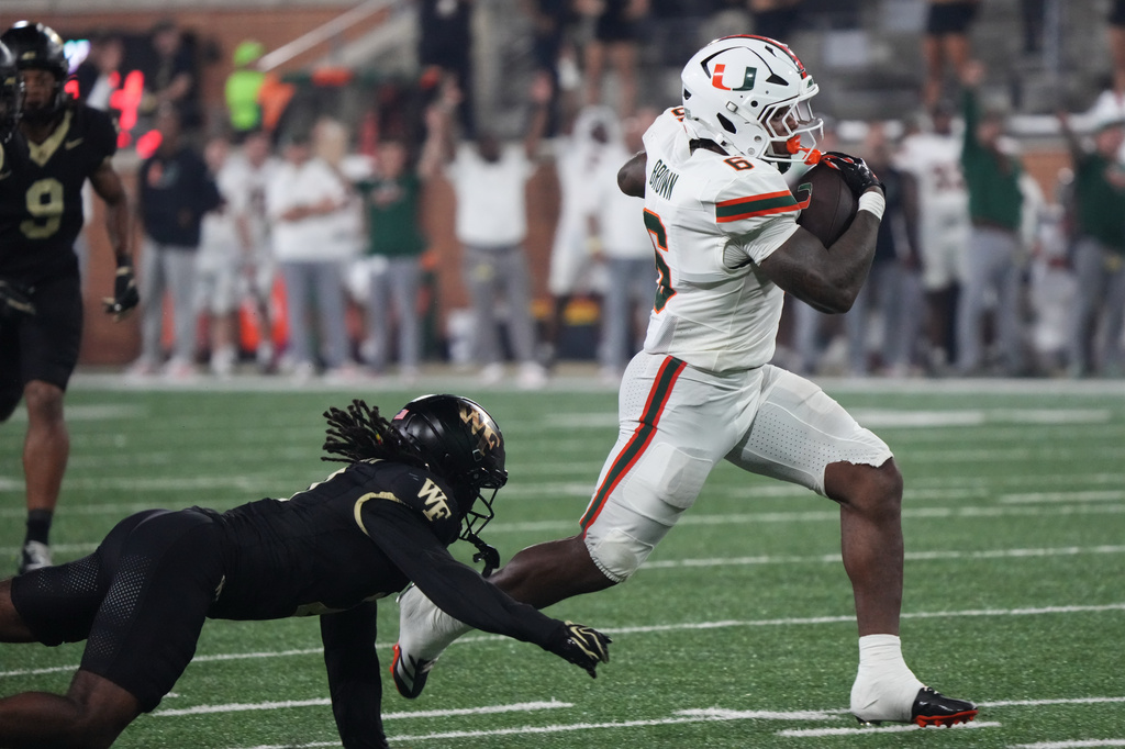 Miami running back Charmar Brown (6) runs as Wake Forest defensive back Ashaad Williams, bottom left, defends during the first half of an NCAA college football game in Winston-Salem, N.C., Friday, Sept. 18, 2026. (AP Photo/Chuck Burton)