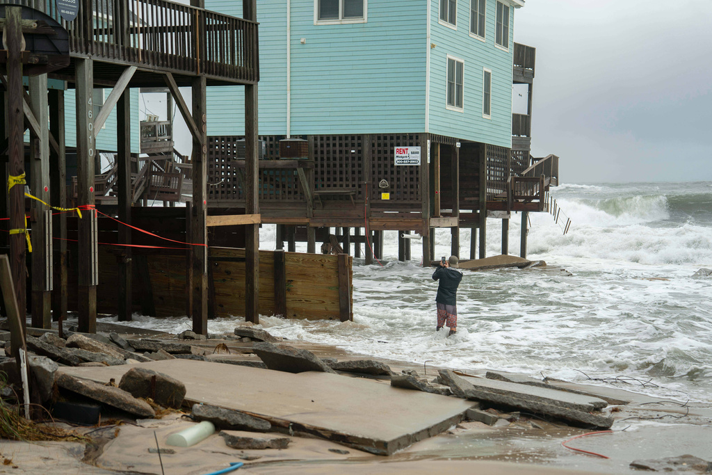 A homeowner takes a photo after a storm, Monday, Oct. 13, 2025, in Buxton, N.C. (AP Photo/Allison Joyce)