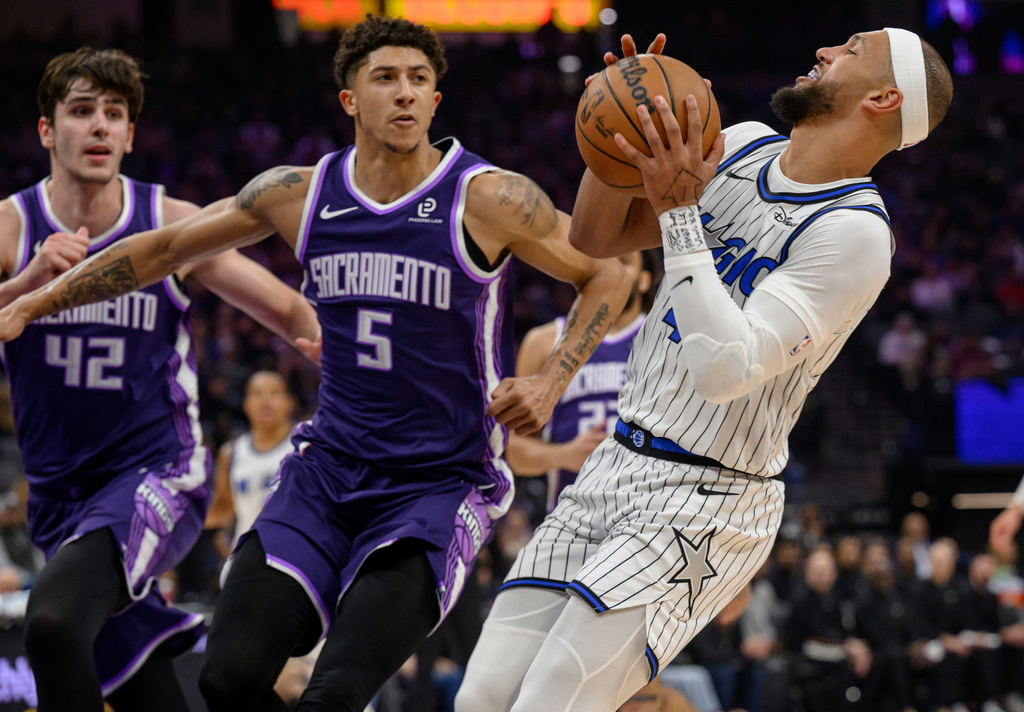 Orlando Magic guard Jalen Suggs, right, is guarded by Sacramento Kings center Maxime Raynaud (42) and guard Nique Clifford (5) during the first half of an NBA basketball game in Sacramento, Calif., Thursday, Feb. 19, 2026. (AP Photo/Randall Benton)