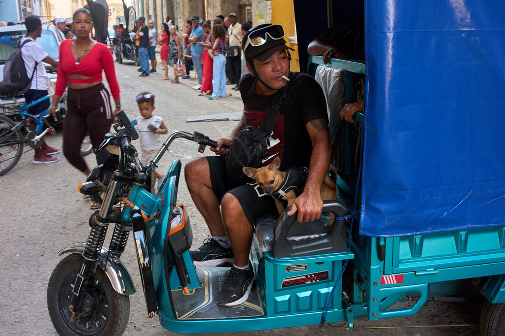 A man maneuvers his electric tricycle alongside his small dog in Havana, Cuba, Wednesday, July 29, 2026. (AP Photo/Ramon Espinosa)