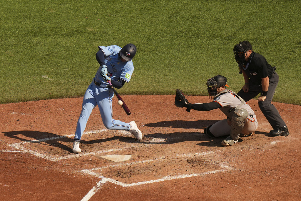 Toronto Blue Jays outfielder Joey Loperfido, left, hits an RBI double in front of Baltimore Orioles catcher Alex Jackson, second from right, during sixth-inning baseball game action in Toronto, Sunday, Sept. 14, 2025. (Chris Young/The Canadian Press via AP)