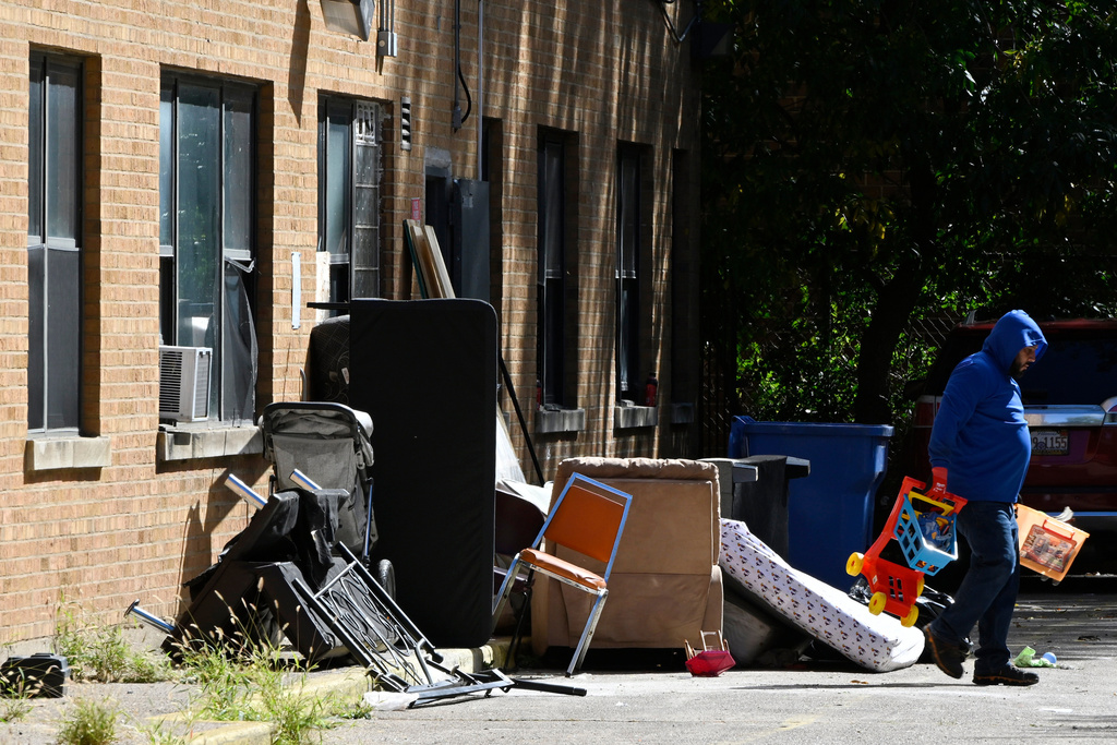 A worker throws away items, Oct. 8, 2025, after ICE agents raided the apartment building at 7500 South Shore Drive in Chicago. (AP Photo/Paul Beaty)