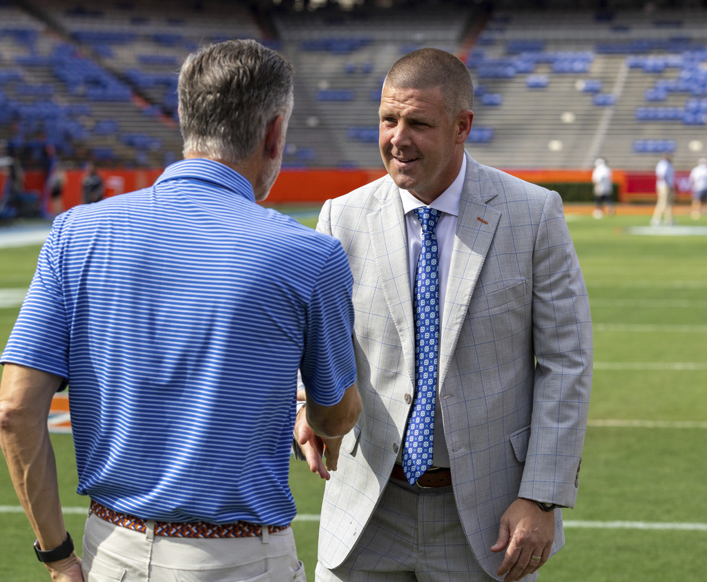 Florida athletic director Scott Strickland, left, greets Florida head coach Billy Napier, right, as he heads to the locker room before an NCAA college football game against LIU Brooklyn, Saturday, Aug. 30, 2025, in Gainesville, Fla. (AP Photo/Alan Youngblood)