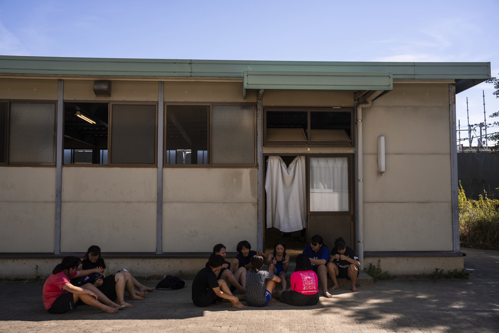 Wrestlers rest outside the dojo after a practice session at a sumo camp in Tottori Johoku High School in Tottori, Japan, on July 28, 2025. (AP Photo/Louise Delmotte)