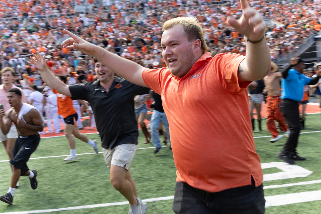 Oklahoma State fans rush the field after the NCAA college football game against Oregon in Stillwater, Okla., Saturday, Sept. 12, 2026. (AP Photo/Mitch Alcala)