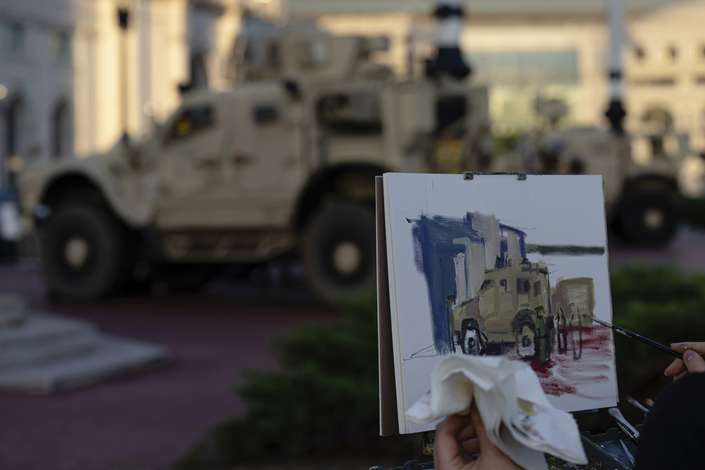 An artist paints a scene featuring DC National Guard Mine Resistant Ambush Protected vehicles (MRAP) at Union Station, Monday, Sept. 1, 2025, in Washington. (AP Photo/Jon Cherry)