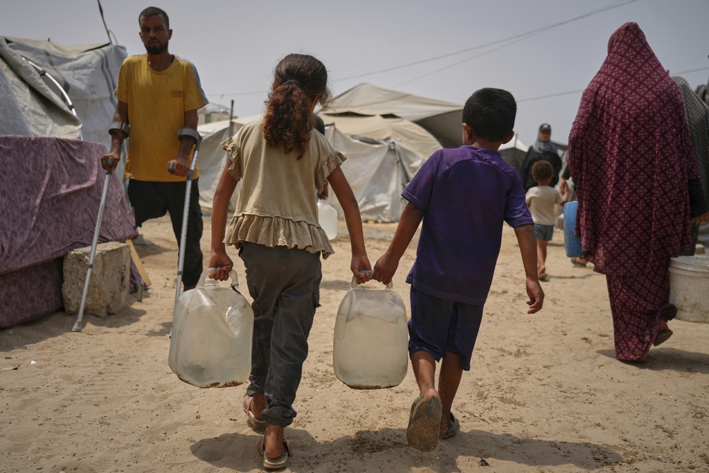 In the summer heat, Palestinian children carry jerrycans after collecting water from a distribution point in Gaza City, Tuesday, Aug. 12, 2025. (AP Photo/Jehad Alshrafi)