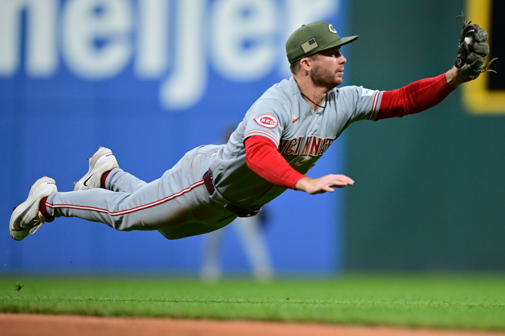 Cincinnati Reds second baseman Matt McLain dives to field a ball hit by Cleveland Guardians' Travis Bazzana during the ninth inning of a baseball game, Friday, May 15, 2026, in Cleveland. (AP Photo/David Dermer)