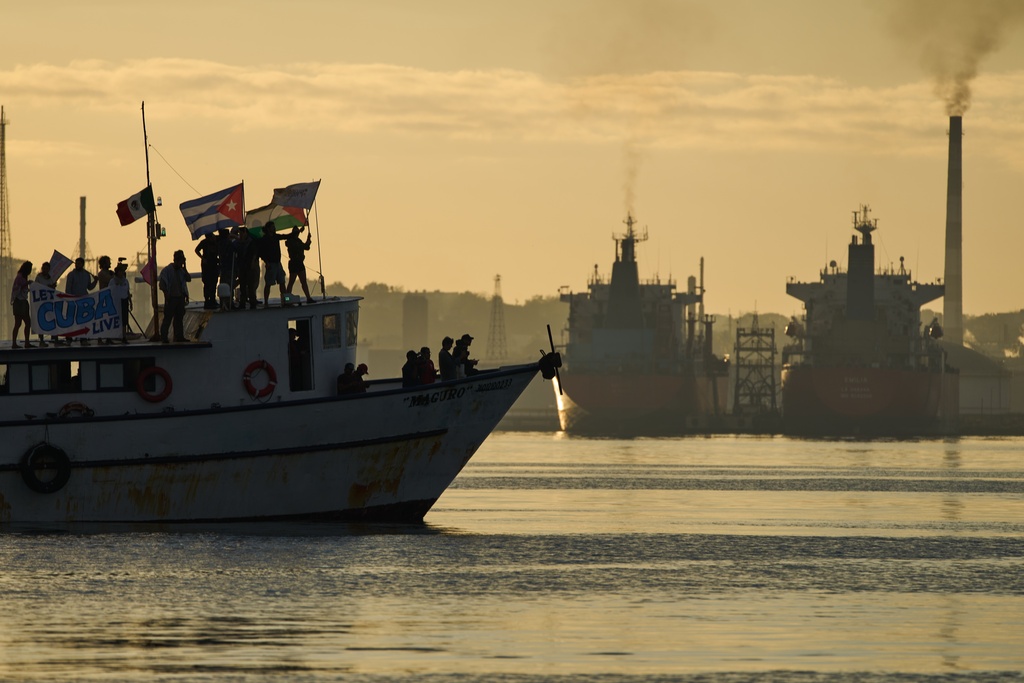 Activists wave Cuban and Palestinian flags from the vessel Maguro, arriving from Mexico with humanitarian aid as part of the "Nuestra America," or Our America convoy, in Havana Bay, Cuba, Tuesday, March 24, 2026. (AP Photo/Ramon Espinosa)