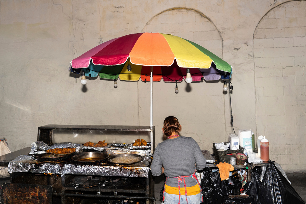 FILE - Street vendor Francisca, an immigrant from Guatemala, prepares an order at her cart in Los Angeles, Tuesday, Aug. 5, 2025, where her son accompanies her to help monitor their surroundings amid ongoing ICE raids. (AP Photo/Jae C. Hong, File)