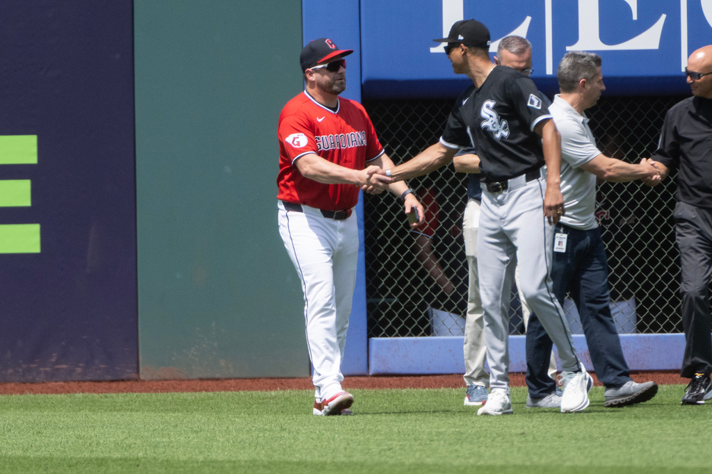 Cleveland Guardians manager Stephen Vogt, left, shakes hands with Chicago White Sox manager Will Venable, front right, after inspecting field repairs before a baseball game, Sunday, July 5, 2026, in Cleveland. (AP Photo/Phil Long)