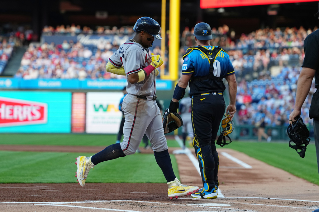 Atlanta Braves' Ronald Acuña Jr. scores past Philadelphia Phillies catcher J.T. Realmuto off of a hit by teammate Ozzie Albies during the first inning of a baseball game, Friday, April 17, 2026, in Philadelphia. (AP Photo/Matt Rourke)