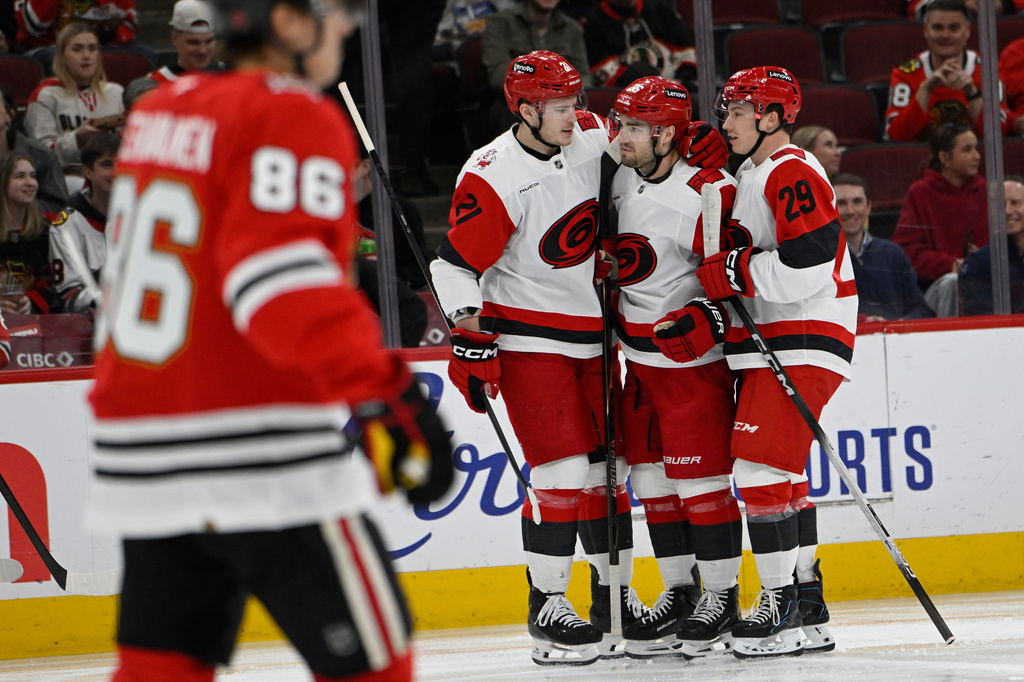 Carolina Hurricanes' Sean Walker (26) celebrates with teammates Alexander Nikishin (21) and Bradly Nadeau (29) after scoring a goal during the first period of an NHL hockey game against the Chicago Blackhawks in Chicago, Thursday, April 9, 2026. (AP Photo/Paul Beaty)